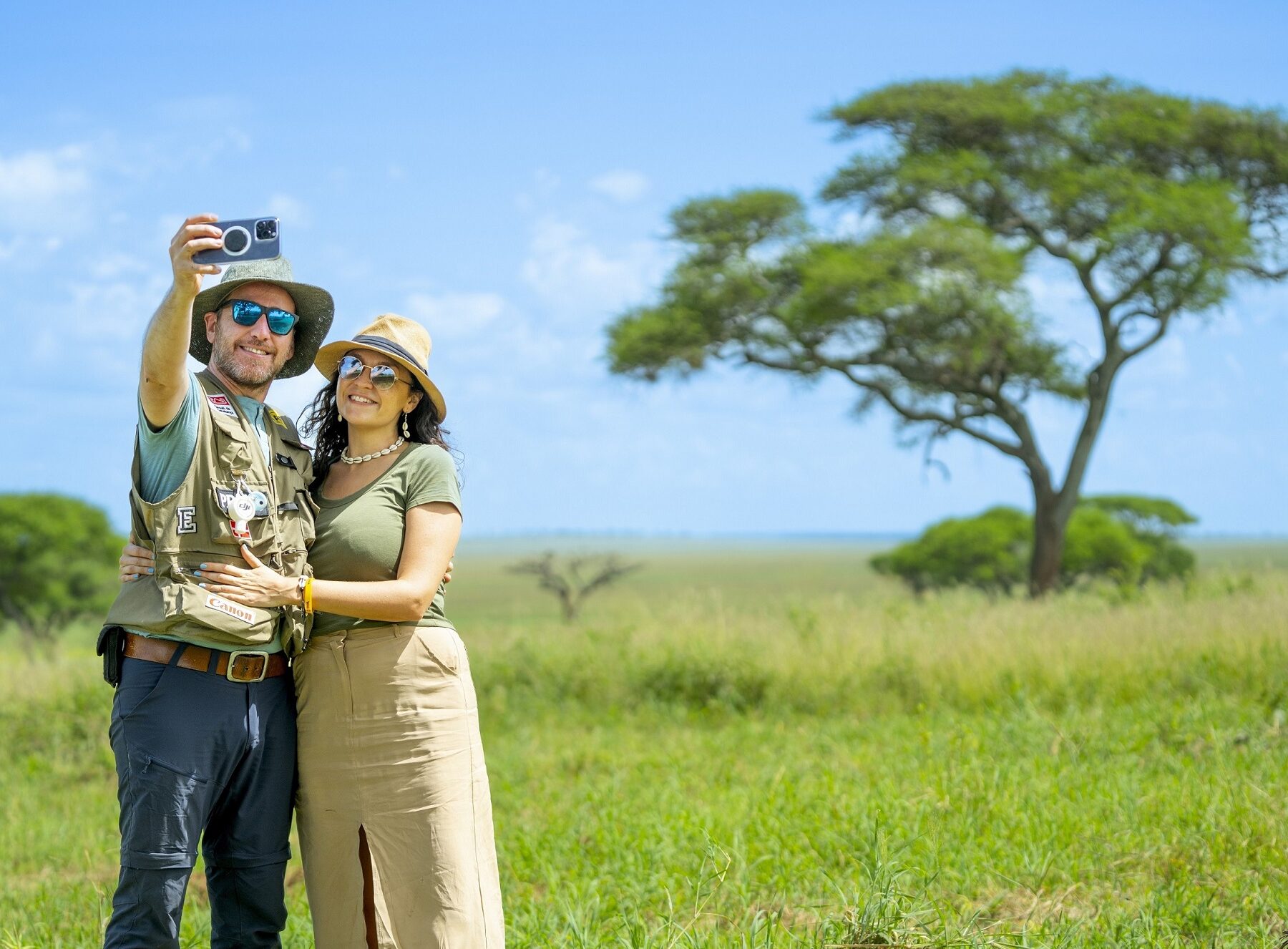 A couple in Tanzania taking a selfie in front of an acacia tree