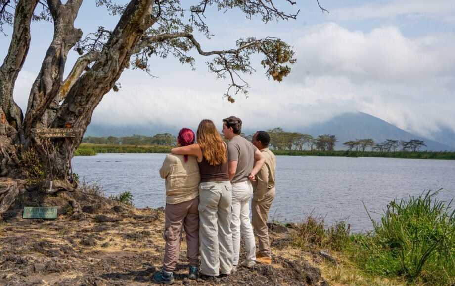 Gruppo di persone con guida che osserva il lago e le montagne in Tanzania